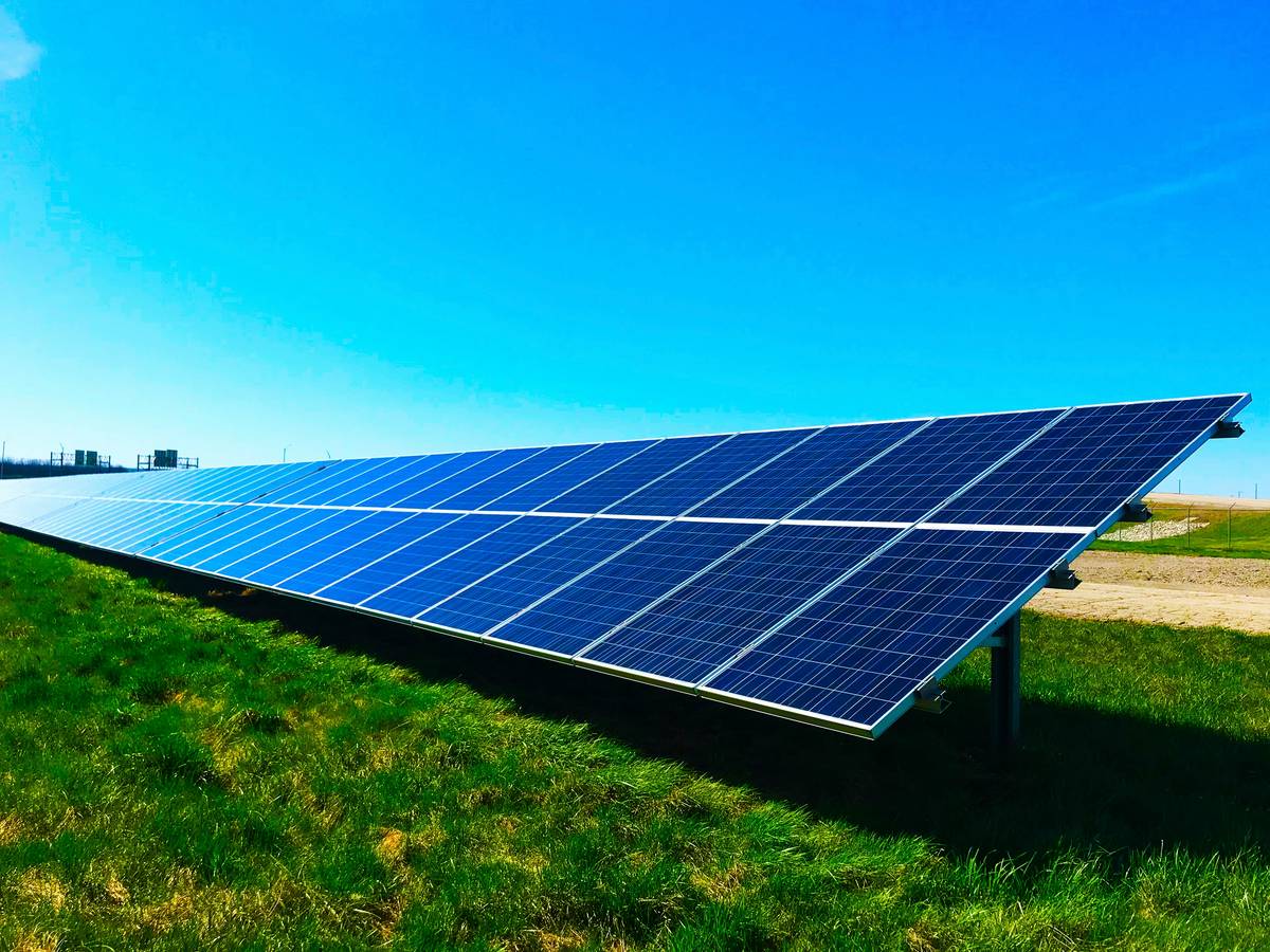 Technician inspecting residential solar panels with solar panel department of energy guidelines on tablet